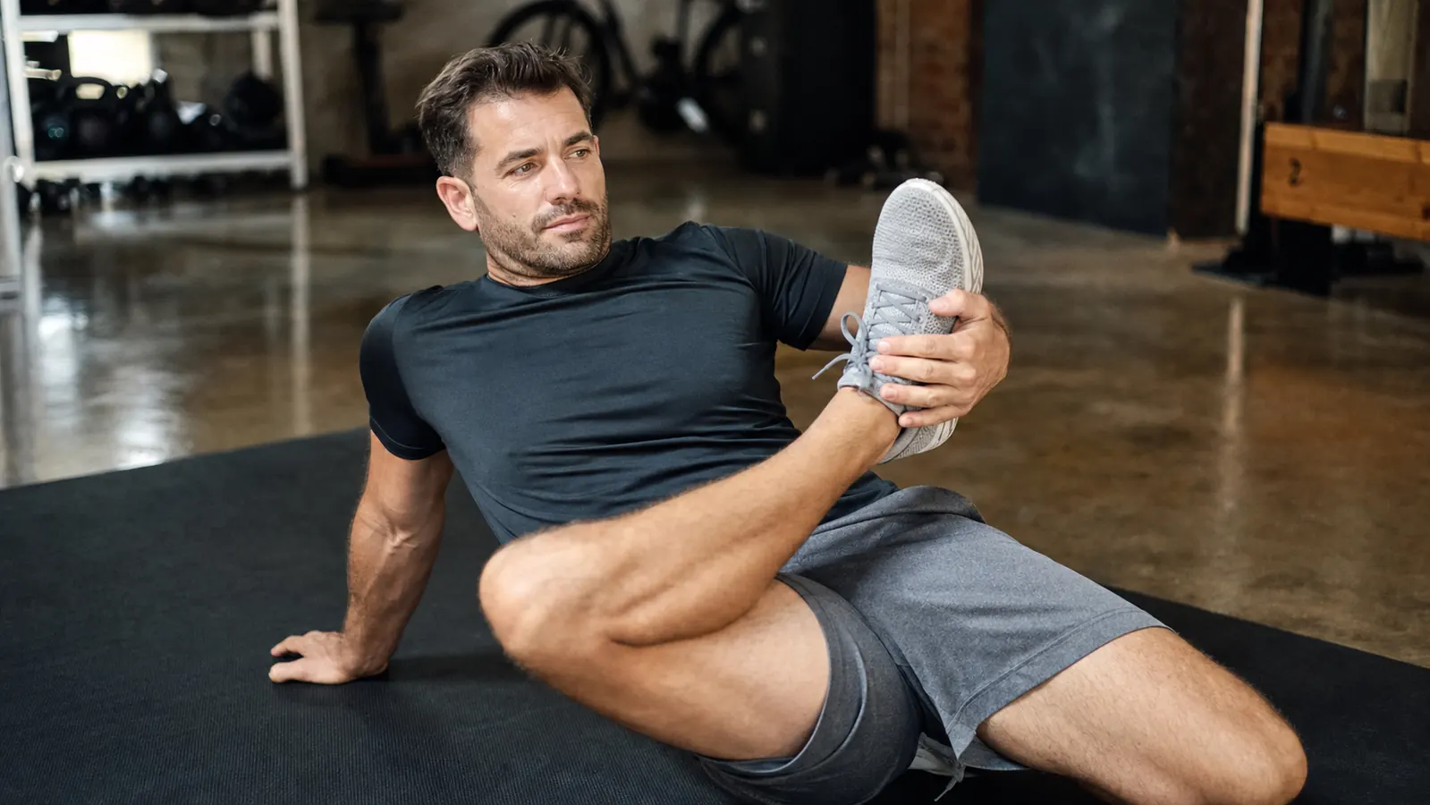 Man sitting on a trail post-run, massage ball in hand, mountains in the background